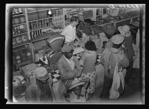 Negro day laborers brought in truck from nearby towns, waiting to be paid off for cotton picking and buy supplies inside plantation store on Friday night. Marcella Plantation. Mississippi Delta. Mississippi