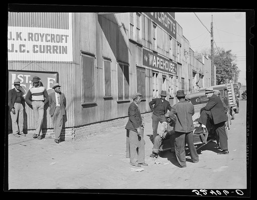Buyer talking to Negro outside tobacco warehouse during auction sales. Durham, North Carolina