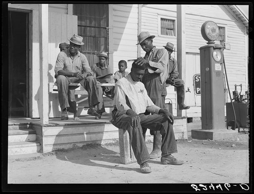 Negroes cut each other's hair in front of plantation store after being paid off on Saturday. Mileston Plantation, Mississippi Delta