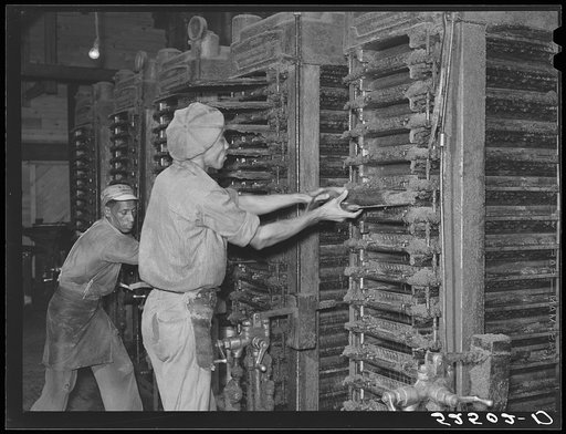 Pulling out cakes of cottonseed meal from press in cotton oil plant. Clarksdale, Mississippi Delta
