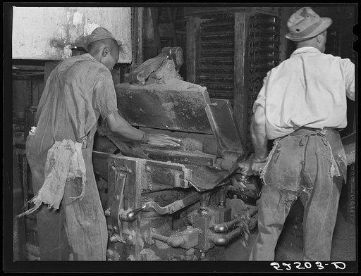 Removing chinese hair mat from cake of cottonseed meal. This meal is fed to cattle. Clarksdale, Mississippi Delta
