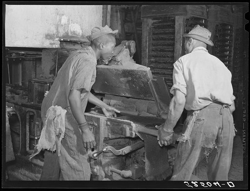Untitled photo, possibly related to: Removing chinese hair mat from cake of cottonseed meal. This meal is fed to cattle. Clarksdale, Mississippi Delta