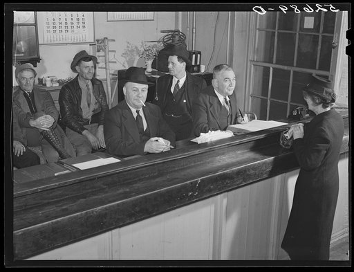 Untitled photo, possibly related to: Sheriff Graham transacting business and then "just visiting" with widow; in background is group of men just killing time during lunch hour on court day in Granville County Courthouse, Oxford, North Carolina