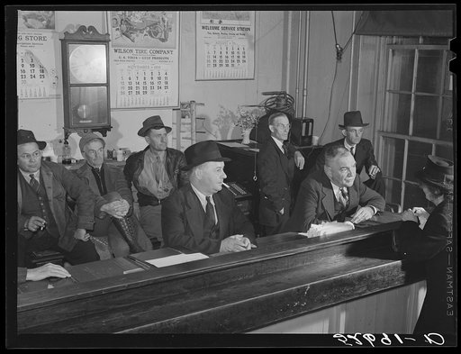 Sheriff Graham transacting business and then "just visiting" with widow; in background is group of men just killing time during lunch hour on court day in Granville County Courthouse, Oxford, North Carolina