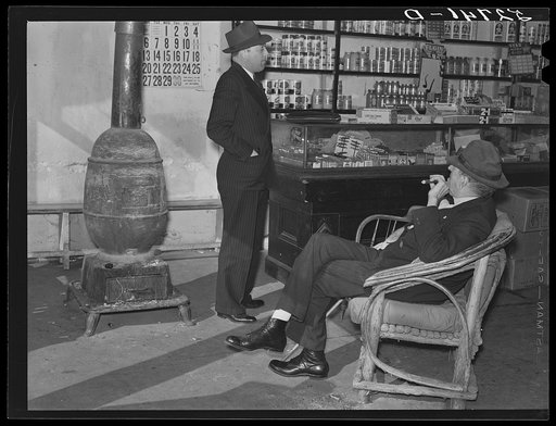 Mr. R.B. Whitley (in chair) visiting in his general store. He is president of the bank and practically owns and runs the town. He is a big landowner, owns Whitley-Davis farm and a cotton mill in Clayton. He said he cut down the trees and pulled up the stumps out of the main street, and was the first