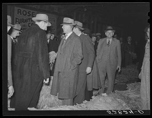 Auctioneer and buyers in warehouse during sale of tobacco. Durham, North Carolina