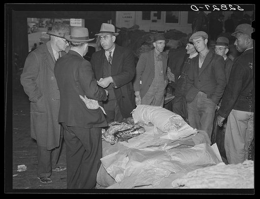 Farmers listening to Armenian bedspread, table linen, and shawl salesman in warehouse during tobacco auctions. Durham, North Carolina