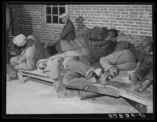 Farmers sleeping in Negro camp room in warehouse. They often must remain overnight or several days before their tobacco is auctioned. Several of them are using an old tobacco basket for a pillow. Durham, North Carolina