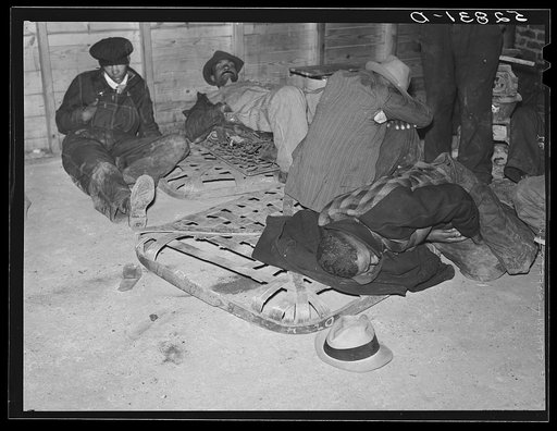 Farmers sleeping in Negro camp room in warehouse. They often must remain overnight or several days before their tobacco is auctioned. One of them is using an old tobacco basket for a pillow. Durham, North Carolina