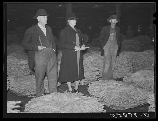 Farmer and his wife waiting for their tobacco to be sold at auction in warehouse. Durham, North Carolina