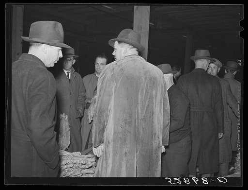 Untitled photo, possibly related to: Warehouseman and auctioneer with buyers in background during tobacco auction sale. Durham, North Carolina
