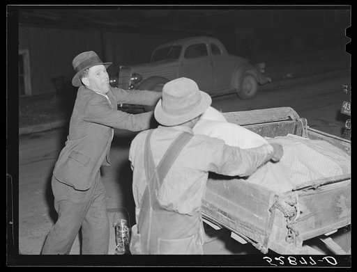 Untitled photo, possibly related to: Mr. Elvin Wilkins fastening a new lantern on the back of his trailer in which he brought his tobacco to the warehouse for auction sale. He is returning home with a bag of hog feed in the trailer. Durham, North Carolina