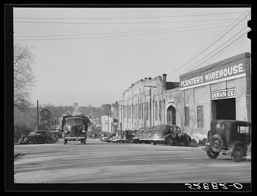 Tobacco warehouses on main street of South Boston, Halifax County, Virginia. A truck is hauling a load of tobacco after the auction. There are eleven warehouses in this small town