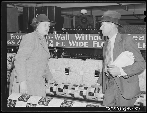 Mr. and Mrs. Elvin Wilkins (Rosa) discussing whether or not they will buy this linoleum for their kitchen floor. They decided it was too light and not wide enough and that they would wait. They came to Durham, North Carolina from their farm near Stem, Granville County, to sell their tobacco at aucti