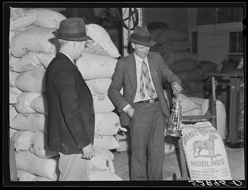 Untitled photo, possibly related to: Mr. Elvin Wilkins fastening a new lantern on the back of his trailer in which he brought his tobacco to the warehouse for auction sale. He is returning home with a bag of hog feed in the trailer. Durham, North Carolina