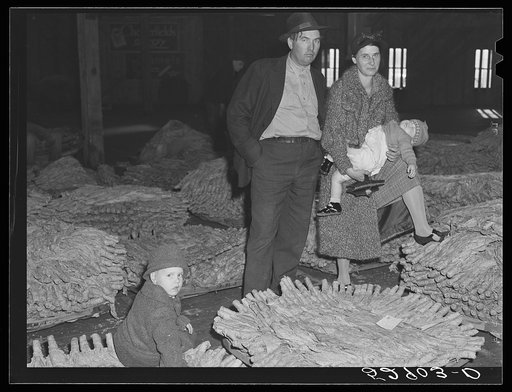 Farmer and his family waiting for their tobacco to be sold at auction in warehouse. Durham, North Carolina