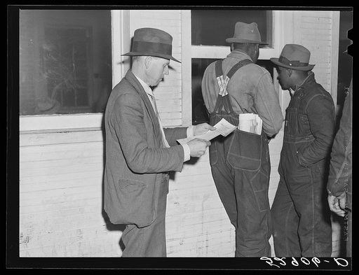 Mr. Elvin Wilkins waiting to get his check for the sale of his tobacco at auction at the warehouse in Durham. Durham County, North Carolina
