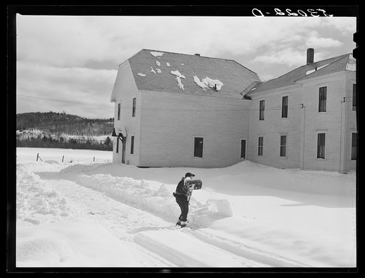 Farmer's son shoveling snow out of driveway near Putney, Vermont