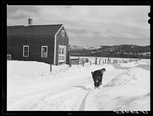 Farmer's son shoveling snow out of driveway near Putney, Vermont