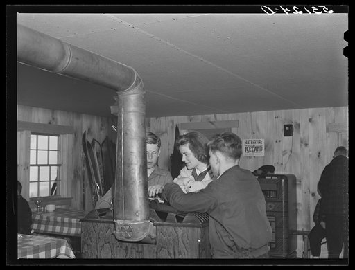 High school students getting warm and drying mittens by stove in ski hut
