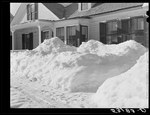Snow slides off the roof and piles high in front of window of farmhouses. Woodstock, Vermont