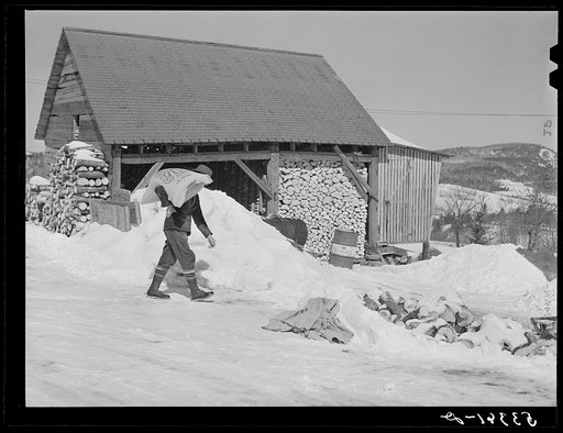 Mr. Dickinson, farmer, carrying sack of cow feed into shed on his farm. Lisbon, near Franconia, New Hampshire