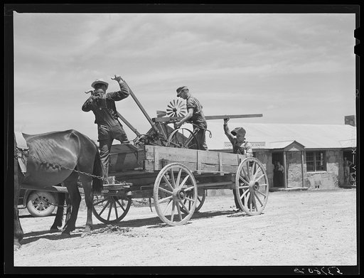 Loading farm machinery onto wagon after repairing at community service center. Faulkner County, Centerville, Arkansas (see general caption)
