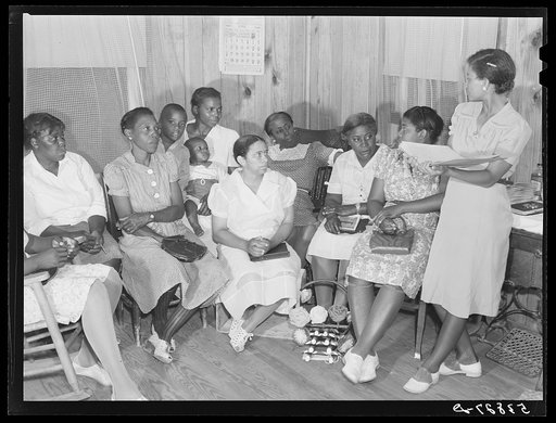 Pearl Cooper, secretary of home demonstration club, reading the report of the previous meeting to the group. Home economist Rachel D. Moore is seated in the background. La Delta Project, Thomastown, Louisiana