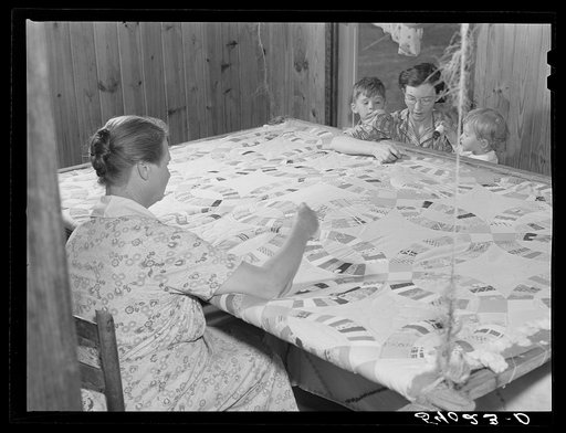 Mrs. Clarence N. Pace with her children and her mother-in-law quilting in their home. Transylvania Project, Louisiana