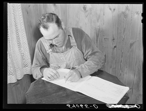 Mr. Verden Lee working on the farm family record book in his home. Transylvania Project, Louisiana