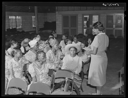 Home management supervisor Corinne Williams has a club group discussion meeting in the assembly building at Okeechobee migratory labor camp. Belle Glade, Florida