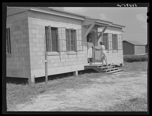 One of the camp members entering health clinic, with nurse Anne Smock in doorway. Osceola migratory labor camp. Belle Glade, Florida