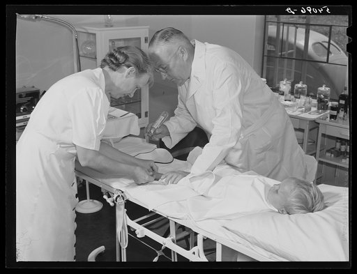 Dr. William J. Buck and nurse Anne Smock dressing infection on child's foot in clinic at Osceola migratory labor camp. Belle Glade, Florida