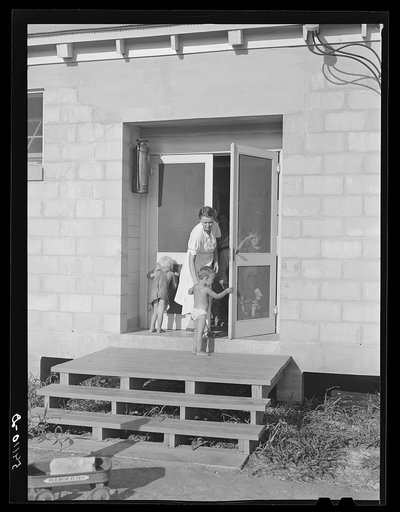 Camp member taking her child into utility building for a shower. Osceola migratory labor camp. Belle Glade, Flordia