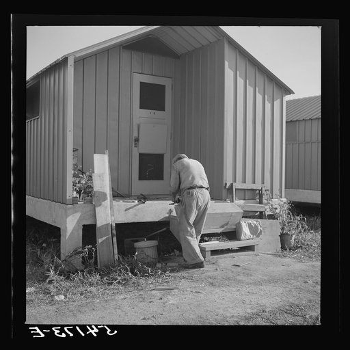 Untitled photo, possibly related to: Camp member who does general carpentry work jobs during slack packing house season builds a window box for his shelter at Osceola migratory labor camp. Belle Glade, Florida