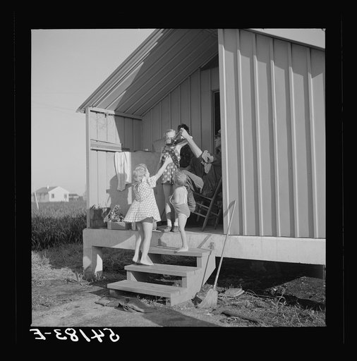 Camp members on porch of their shelter eager for a drink of good water available at the head of each shelter unit. Osceola migratory labor camp,  Belle Glade, Florida