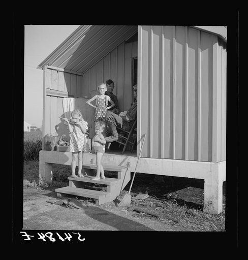 Untitled photo, possibly related to: Camp members on porch of their shelter eager for a drink of good water available at the head of each shelter unit. Osceola migratory labor camp,  Belle Glade, Florida