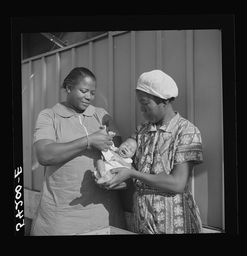 The nurse examines one of the camp's first babies. Mother and child are given both prenatal and postnatal care by nurse and doctor at clinic too. Okeechobee migratory labor camp. Belle Glade, Florida