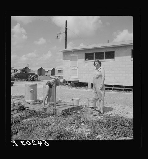 Running water and garbage and refuse disposal cans are placed at head of each shelter unit division in Osceola migratory labor camp. Belle Glade, Florida