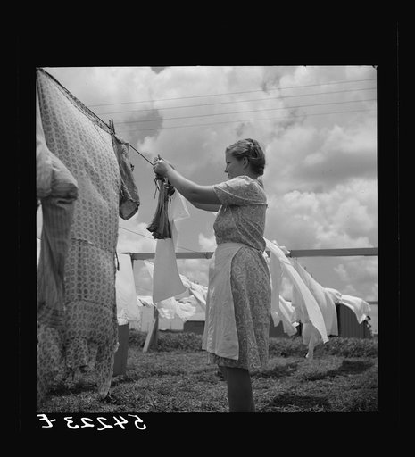 Untitled photo, possibly related to: Camp member hanging out clothes outside of utility building which is equipped with complete laundry facilities and showers. Osceola migratory camp, Belle Glade, Florida