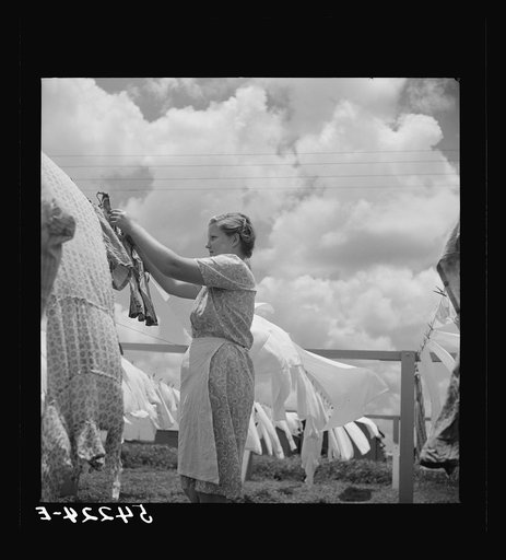 Camp member hanging out clothes outside of utility building which is equipped with complete laundry facilities and showers. Osceola migratory camp, Belle Glade, Florida