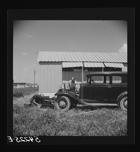 Camp member repairing his car outside his shelter. Osceola migratory labor camp. Belle Glade, Florida