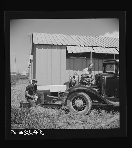 Untitled photo, possibly related to: Camp member repairing his car outside his shelter. Osceola migratory labor camp. Belle Glade, Florida