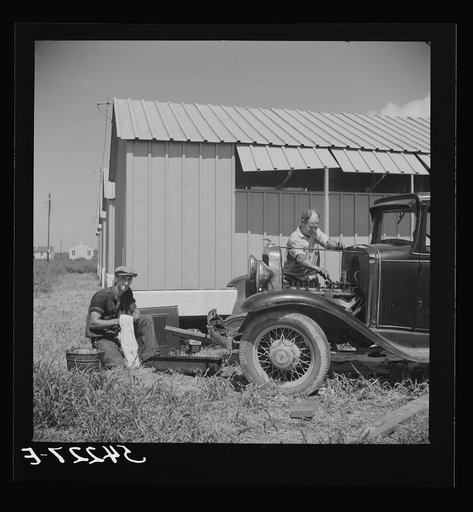Untitled photo, possibly related to: Camp member repairing his car outside his shelter. Osceola migratory labor camp. Belle Glade, Florida