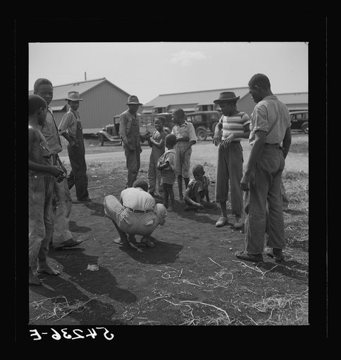 Camp members' children playing marbles outside their shelter units at Okeechobee migratory labor camp. Belle Glade, Florida