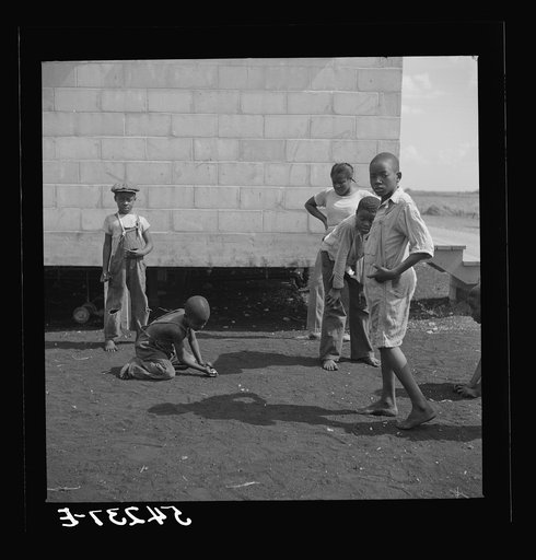 Untitled photo, possibly related to: Camp members' children playing marbles outside their shelter units at Okeechobee migratory labor camp. Belle Glade, Florida