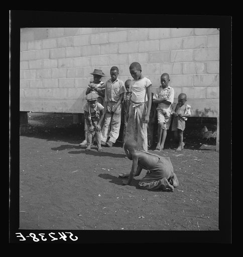 Camp members' children playing marbles outside their shelter units at Okeechobee migratory labor camp. Belle Glade, Florida