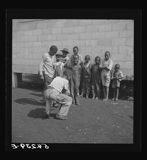Untitled photo, possibly related to: Camp members' children playing marbles outside their shelter units at Okeechobee migratory labor camp. Belle Glade, Florida
