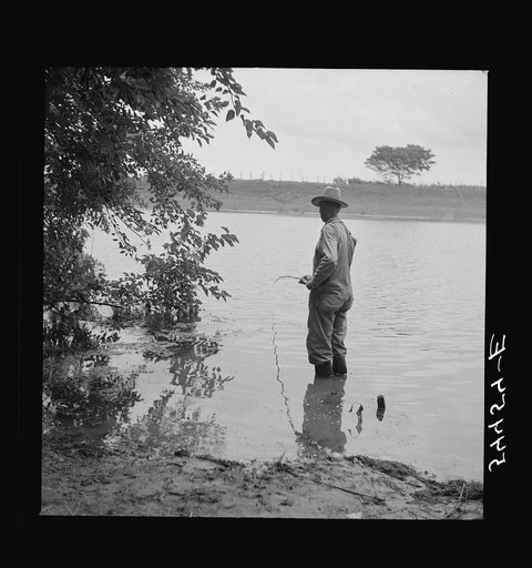 Farmer fishing in Cane River on Fourth of July. Near Natchitoches, Louisiana