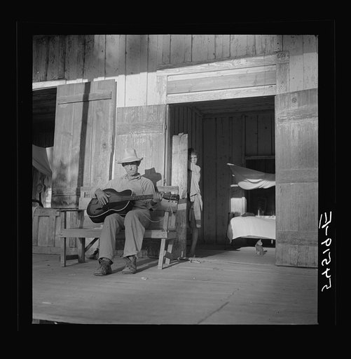 Farmer playing guitar on the porch in the evening. Near Natchitoches, Louisiana